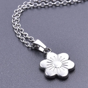 Detailed macro view of silver stainless steel six-petal flower pendant with radial engraving