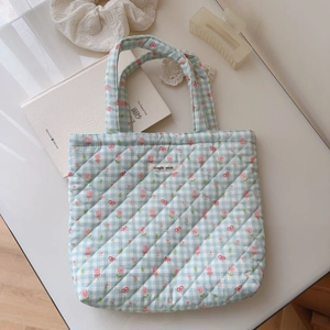 Detail of blue plaid quilted tote bag with pink floral patterns and a simple wish tag