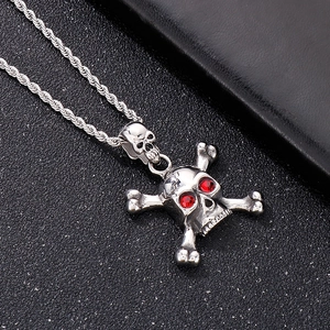 Detailed macro shot of silver skull pendant with red eyes and bone accents on black