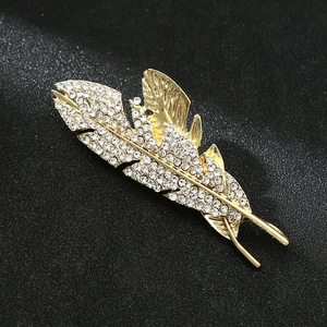 Detailed macro view of a golden feather brooch with crystal rhinestones on black background