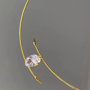 Gros plan d'un pendentif ovale en zircon doré sur un collier minimaliste en métal poli