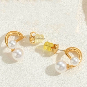 Macro view of gold heart pearl earrings with secure metal and clear plastic backings