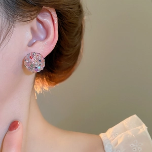 Close-up of elegant pink sphere earrings with shimmering crystals on a female model