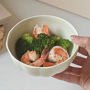 Close-up of a light green ceramic bowl filled with fresh shrimp and steamed broccoli