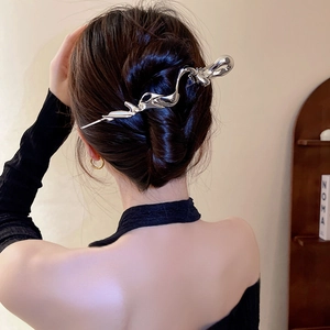 Detail of silver liquid metal hair clip worn on model with irregular streamlined design