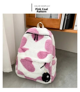 Detailed close-up of fluffy pink and white cow print backpack with plush soot sprite charm