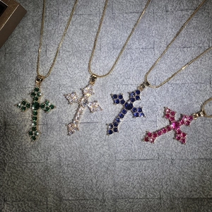 Detail of four colorful cross necklaces with emerald, sapphire, white and rose crystals