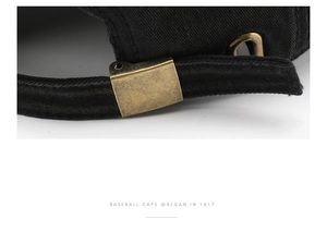 Detail of adjustable bronze metal buckle on vintage washed black denim baseball cap