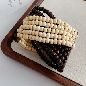 Close-up of bohemian layered coconut shell wood bead bracelet in a wooden tray