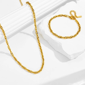 Golden stainless steel woven chain jewelry set with necklace and bracelet on white stone