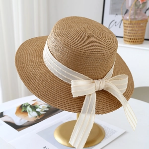 Detail of hand-woven straw hat with large cream chiffon bow on a display stand