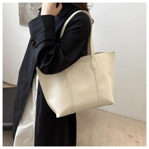 Sac fourre-tout crème minimaliste en cuir porté avec un long manteau noir d'hiver