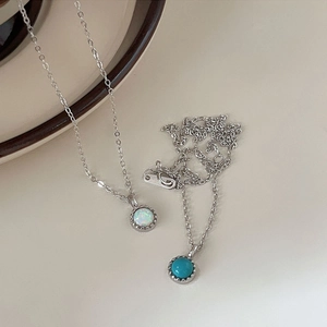 Close-up of minimalist S925 silver turquoise and opal pendants with delicate beaded edges