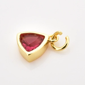Detail of a triangle red zircon pendant with polished gold base on a white background