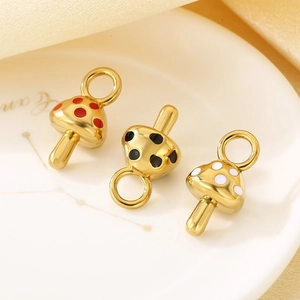 Macro detail of three gold mushroom enamel pendants in red, black, and white dot styles