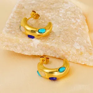 Retro gold titanium hoop earrings with turquoise and opal stones on luxury background