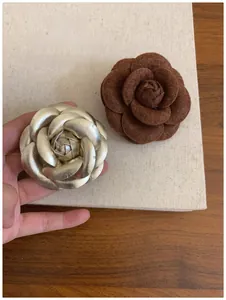 Macro detail of camellia brooches in gold metal and dark brown flocked fabric textures