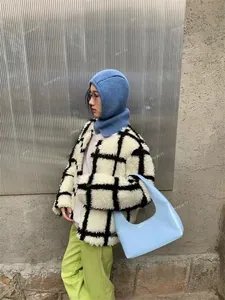 Detail of light blue patent leather crescent bag paired with a checkered plush jacket
