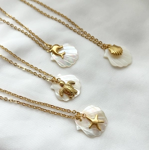 Detail of four gold 18K ocean pendants with white shells including dolphin and sea turtle