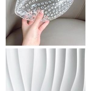 Detail of transparent acrylic clutch featuring embedded crystals and white wavy texture