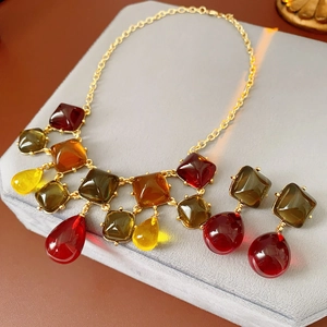 Dettaglio di orecchini pendenti e collana in resina vintage su supporto di velluto