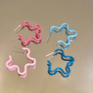 Boucles d'oreilles étoiles en émail au design ondulé sur une surface réfléchissante
