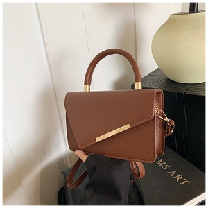 Detail of brown litchi pattern leather bag with asymmetrical gold clasp and top handle