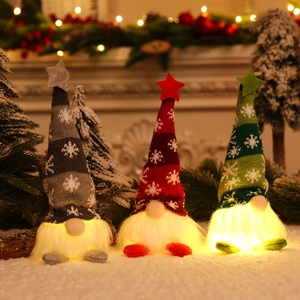 Three glowing Christmas gnomes with knit hats and warm LED lights on a snowy display