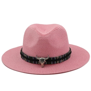 Detail of pink straw fedora with ethnic band and silver metallic bull skull charm