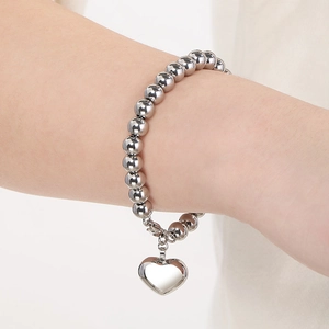 Vue détaillée du bracelet à billes argentées avec un pendentif cœur sur le poignet