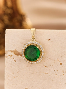 Macro shot of green zircon pendant with white stones in gold four-claw setting