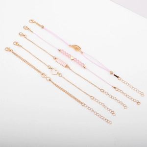 Detail view of 5-piece gold and pink bracelet set featuring leaf, heart, and infinity charms