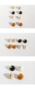 Detailed macro view of four colors of round enamel stud earrings with gold metal tops