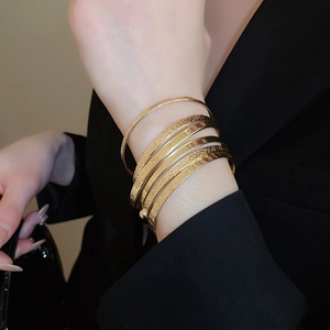 Detail view of 6-piece gold metal bangle set with varied textures and LOVE engraving
