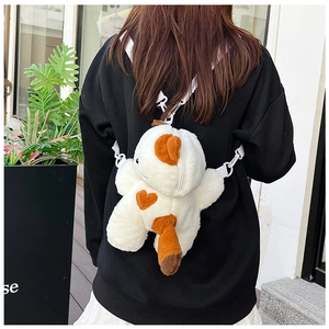 Detail of white plush dinosaur crossbody bag with orange heart embroidery and strap