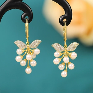 Detail of gold butterfly pearl tassel earrings with zircons on jewelry stand