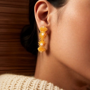 Détail de boucles d'oreilles fleuries plaquées or 18k avec zircons sur le mannequin