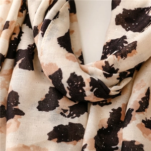 Dettaglio ravvicinato di sciarpa leopardata con glitter argento e frange intrecciate