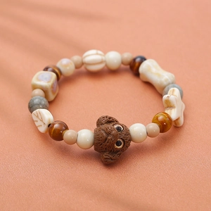 Gros plan détaillé d'une perle de chien teddy en céramique sur un bracelet avec breloques d'os