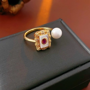 Close-up of gold plated ring with red gemstone, small diamonds and a white pearl