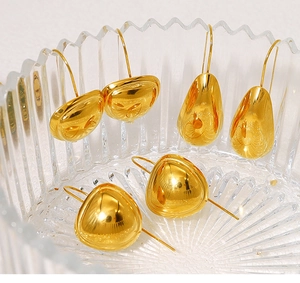 Polished 18K gold waterdrop earrings displayed in a textured glass bowl for jewelry detail