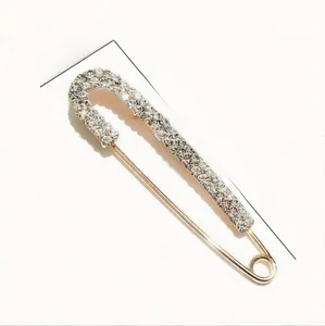 Safety pin brooch in gold finish with sparkling rhinestones measuring 1.4cm by 6.2cm