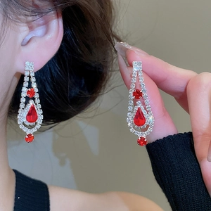 Detail of silver drop tassel earrings with sparkling red rhinestones on a model