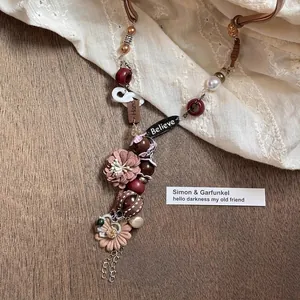 Detail of bohemian necklace with handmade flower, Believe tag and vintage wood beads