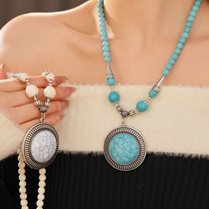 Close-up of bohemian beaded necklaces with turquoise and marble pendants on knitwear