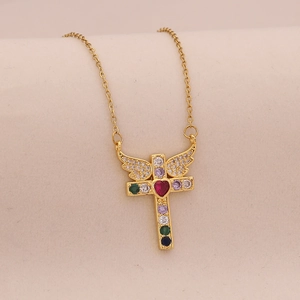 Detailed close-up of a gold cross necklace with colorful gems and winged heart pendant