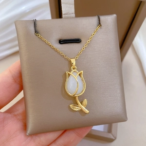 Macro detail of tulip pendant with white oval gemstone on a golden titanium necklace