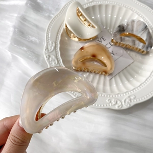 Detailed view of elegant leopard acetate hair claws with metallic gold-tone grip teeth