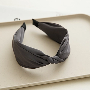 Detailed close-up of a charcoal grey satin knotted headband on a ceramic tray