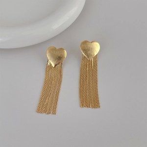 Macro detail of golden heart earrings featuring long cascading metallic tassels and texture